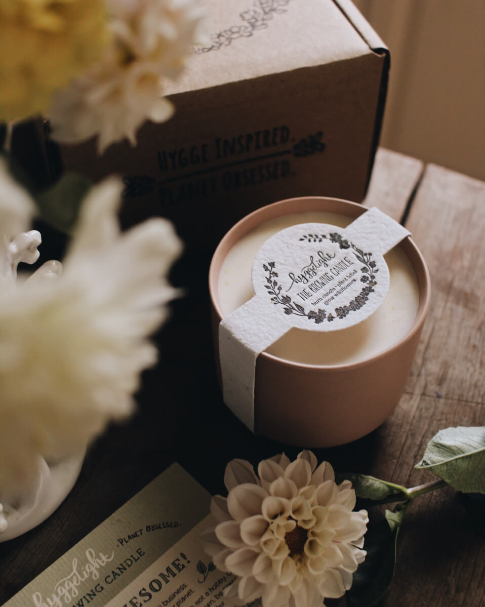 The Adelyn Growing Candle beside flowers and zero-waste packaging from company Hyggelight in Toledo, Ohio.