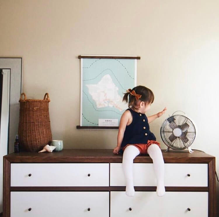 Mom looks on as little girl sits on top of dresser